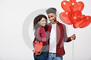 Young attactive African American couple holding heart balloon and paper.