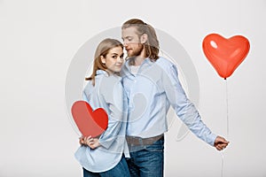 Young attactive caucasian couple holding heart balloon and paper.