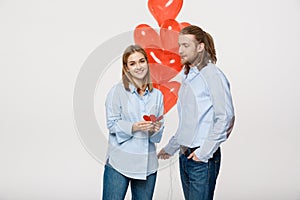 Young attactive caucasian couple holding heart balloon and paper.