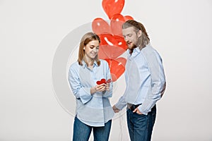 Young attactive caucasian couple holding heart balloon and paper.