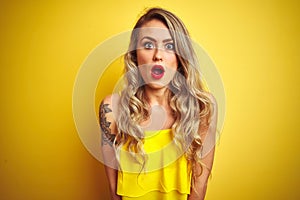 Young attactive woman wearing t-shirt standing over yellow isolated background afraid and shocked with surprise expression, fear