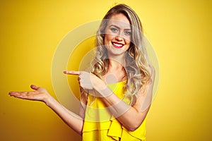 Young attactive woman wearing t-shirt standing over yellow isolated background amazed and smiling to the camera while presenting