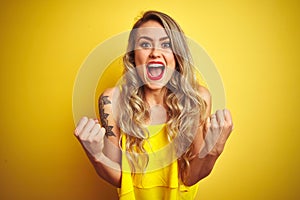 Young attactive woman wearing t-shirt standing over yellow isolated background celebrating surprised and amazed for success with