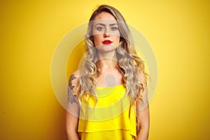 Young attactive woman wearing t-shirt standing over yellow isolated background Relaxed with serious expression on face