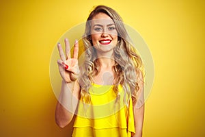 Young attactive woman wearing t-shirt standing over yellow isolated background showing and pointing up with fingers number three