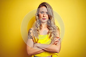 Young attactive woman wearing t-shirt standing over yellow isolated background skeptic and nervous, disapproving expression on