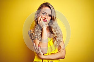Young attactive woman wearing t-shirt standing over yellow isolated background thinking looking tired and bored with depression