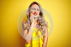 Young attactive woman wearing t-shirt standing over yellow isolated background touching mouth with hand with painful expression