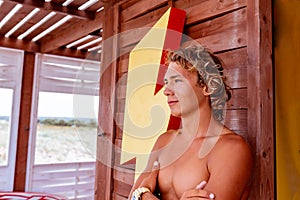 Young attceractive guy surfer standing on the terrace of a surf school looking out into the distance