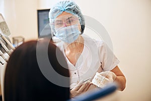 Young attentive stomatologist looking at her patient