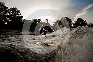 Young attractive active man riding on the wakeboard on the lake