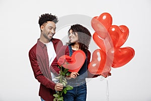 Young attractive african american couple on dating with red rose,heart and balloon.