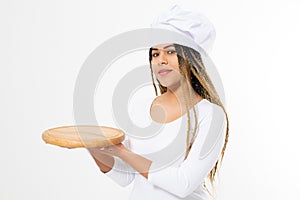 Young attractive african american woman in cooking hat holding empty wood pizza cutting board isolated on white background. Copy