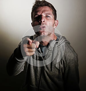 Young attractive angry and upset man looking with intense and threatening eyes as if scolding pointing with the finger in aggressi