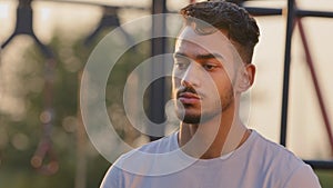 Young attractive Arabic male student of sports university or coach looks pensively aside, chooses training program