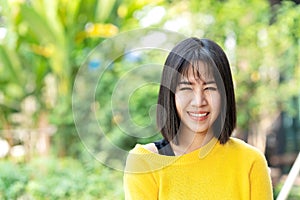 Young attractive asian creative designer woman standing, smiling, looking at camera feeling happy and positive with nature outside