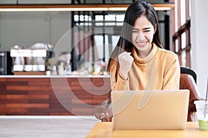 Young attractive asian female student using laptop computer smiling with excited at cafe coffee shop. Happy asian success woman,