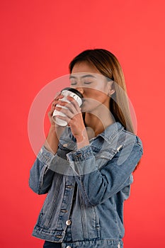 Young attractive asian girl drinking coffee in studio