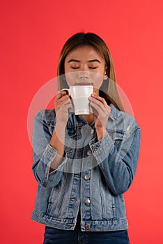 Young attractive asian girl smelling coffee