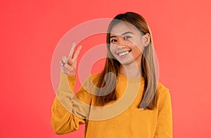 Young attractive asian girl smiling with peace sign in studio