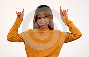 Young attractive asian girl smiling with rock n roll pose in studio