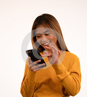 Young attractive asian girl smiling while using smartphone in studio
