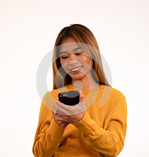 Young attractive asian girl smiling while using smartphone in studio