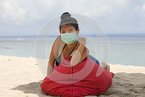 Young attractive Asian Korean woman enjoying beach holidays wearing bikini and protective facial mask in prevention vs virus