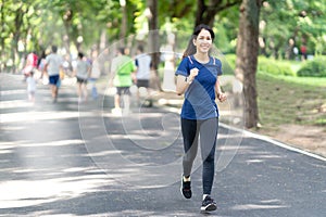 Young attractive asian runner woman running in urban public nature park in city