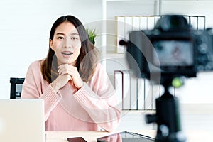 Young attractive asian woman blogger or vlogger looking at camera and talking on video shooting with technology. Social media