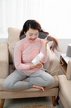 Young attractive asian woman dries her hair