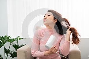 Young attractive asian woman dries her hair