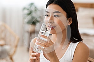 Young attractive asian woman drinking water, copy psace