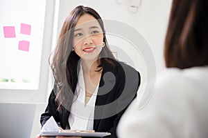 A young attractive asian woman is interviewing for a job. Her interviewers are diverse.