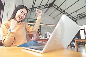 Young attractive asian woman looking at laptop computer feeling happy cheerful or excited expression success or win