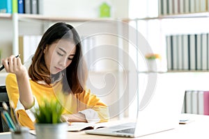 Young attractive asian woman or student working on thesis assignment or studying online in self e-learning education program. photo