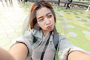 Young attractive Asian woman tourist taking a photo of selfie in urban city