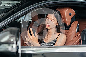 Young attractive asian woman using phone while sitting in a luxury car front sea