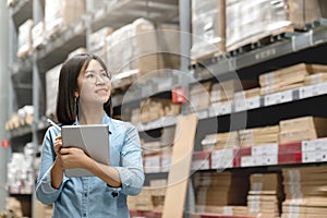 Young attractive asian worker, owner, entrepreneur woman holding smart tablet computer looking side up above shelf with