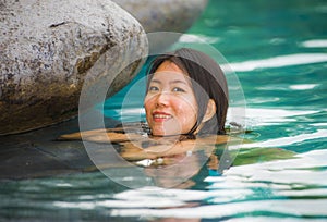 Young attractive and beautiful Asian Korean woman relaxing happy at tropical beach luxury resort swimming at jungle infinity pool