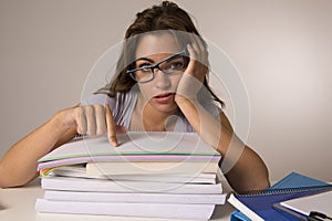 Young attractive and beautiful tired student girl leaning on school books pile sleeping tired and exhausted after studying