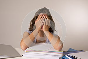 Young attractive and beautiful tired student girl leaning on school books pile sleeping tired and exhausted after studying