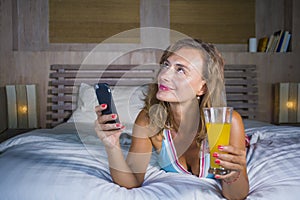 Young attractive and beautiful woman at home in bed using internet social media app on mobile phone smiling happy drinking healthy