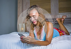Young attractive and beautiful woman at home in bed using internet social media app on mobile phone smiling happy relaxed