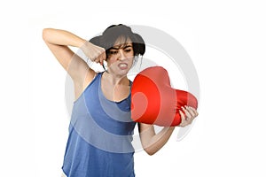 Young attractive and beautiful woman punching in rage spiteful and resentful a red heart shape pillow