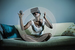 Young attractive black afro American woman playing amazed and surprised virtual reality video game wearing VR goggles