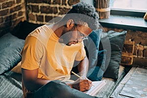 Young attractive black man with dark skin write down in the paper notebook.Hand writing, Learning and education