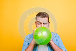 Young attractive blond man tired to blow up balloons new year pa