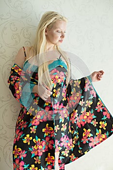 Young attractive blonde in a bright nightgown and bright robe with flower pattern