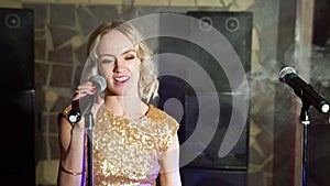 Young attractive blonde woman dancing and singing with microphone